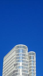 Low angle view of modern building against blue sky