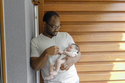 Father holding hand of daughter and leaning on wall at doorway