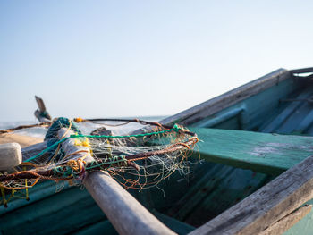 Close-up of fishing net on wooden post against clear sky