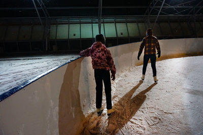 Rear view of people ice-skating at night