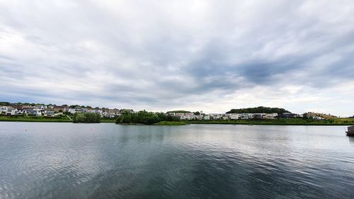 Scenic view of river by buildings against sky