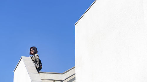 Low angle view of lady against blue sky