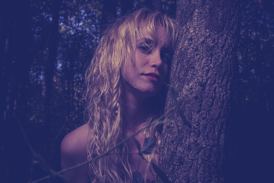 Close-up portrait of young woman standing by tree