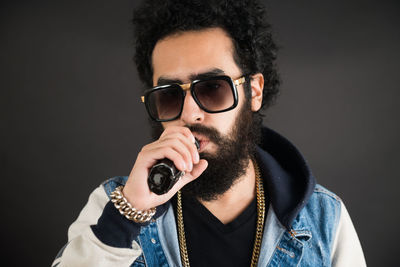 Portrait of young man vaping against black background