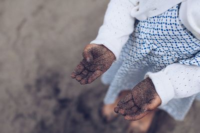 High angle view of a girls hands full of sand