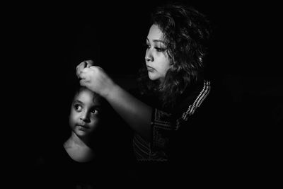 Portrait of mother and daughter against black background