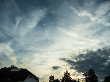 Low angle view of silhouette trees and buildings against sky