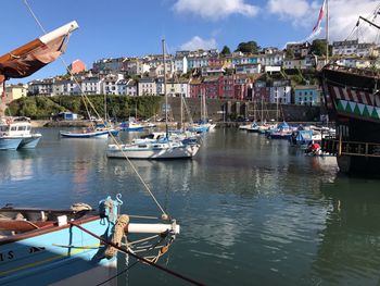 Sailboats moored in harbor by city against sky