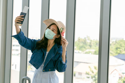Portrait of young woman looking through window