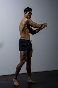 Shirtless muscular man exercising against wall