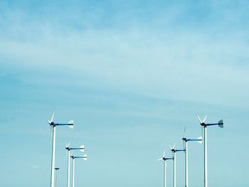 Low angle view of windmills against blue sky