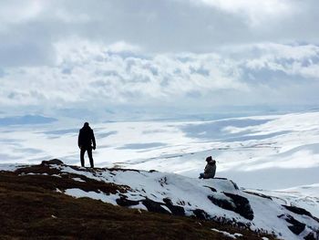 Rear view of man standing on snow covered mountain