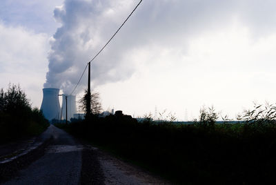 Road by factory against sky