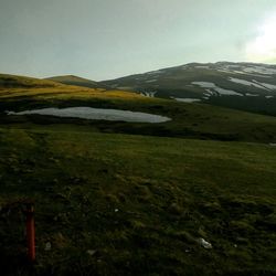 Scenic view of green landscape and mountains against sky