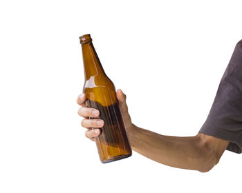 Close-up of hand holding glass bottle against white background