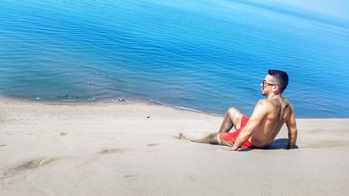 Young man sitting on shore at beach
