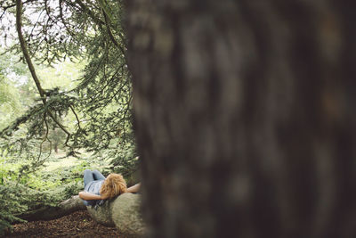 Woman lying on tree root