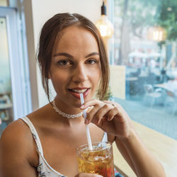 Portrait of a smiling young woman drinking glass