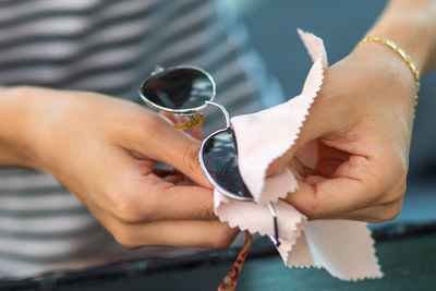 Cropped image of woman wiping sunglasses