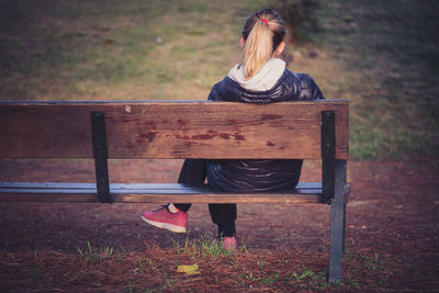 Rear view of woman sitting on bench in park