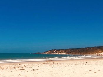 Scenic view of beach against clear blue sky