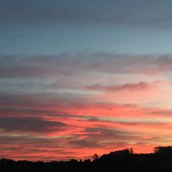 Low angle view of silhouette trees against dramatic sky