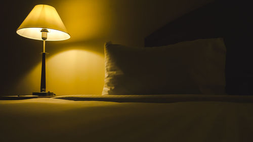 Illuminated lamp on bed at home