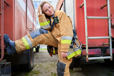 Young female fighter standing by fire truck