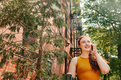 Portrait of smiling young woman against plants