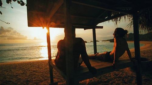 Woman sitting on beach at sunset