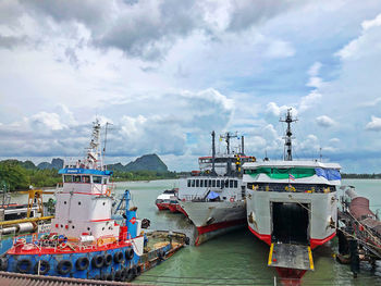 Fishing boats moored at harbor against sky