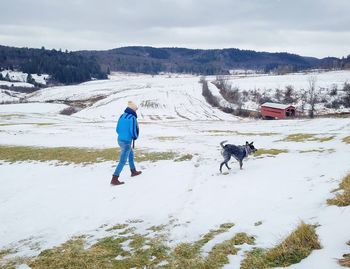 View of man with dog on snow covered land