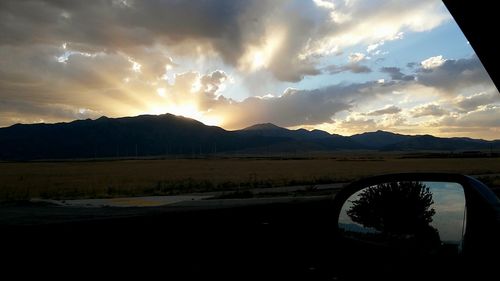 Scenic view of mountains against cloudy sky at sunset