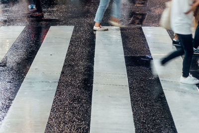 Low section of people walking on wet road