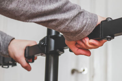 The hands of a young caucasian guy sets up a bracket for a monitor in his room 