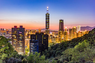 Illuminated cityscape against sky at night