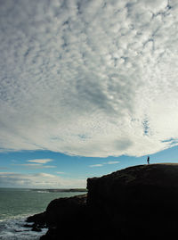 Silhouette rocks on beach against sky