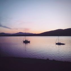 Silhouette sailboats in sea against sky during sunset