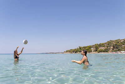 Happy teenagers playing volleyball in water at the vacation and fun