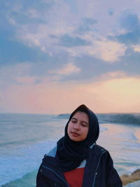 Portrait of teenage girl at beach against sky during sunset