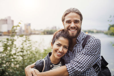 Portrait of smiling couple standing against river
