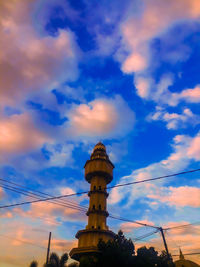 Low angle view of tower and building against sky during sunset