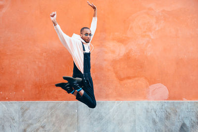 Full length of young man jumping against wall