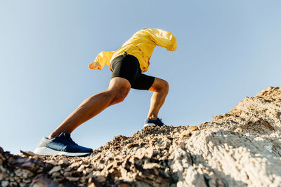 Low angle view of man on rock against sky