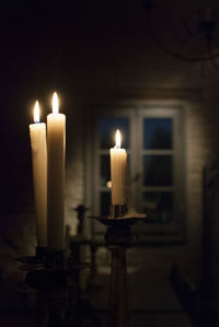 Close-up of lit candles in darkroom