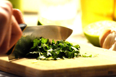 Close-up of hand holding vegetables on cutting board