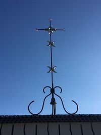 Low angle view of weather vane against blue sky