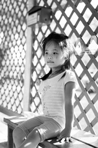 Cute girl looking away while sitting on bench