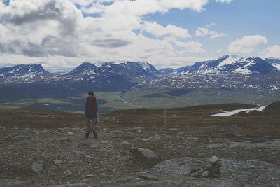 Rear view of female hiker looking at mountains against sky at abisko national park