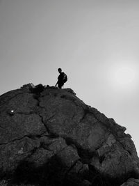Silhouette man standing on rock against clear sky